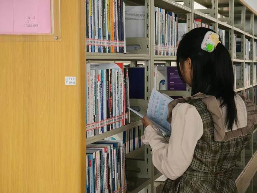 人在书架前  AI 生成的内容可能不正确。